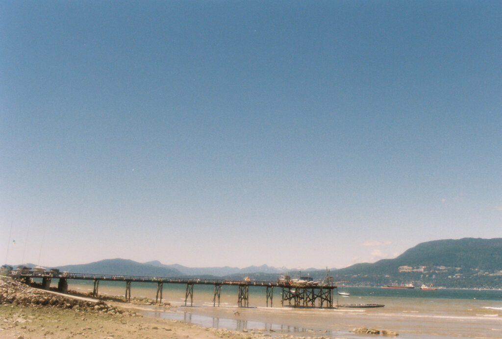 Colour photo with low horizon wooden pier extending out into English bay